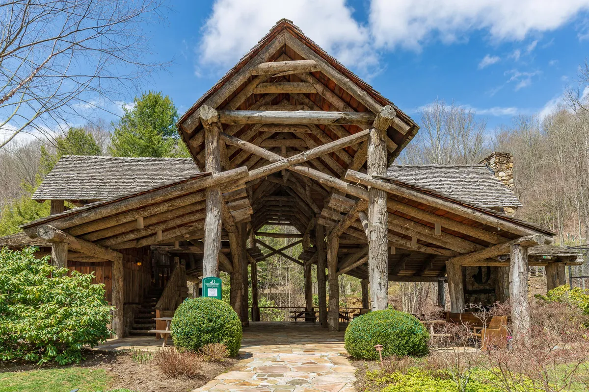 A rustic log structure sits beside a winding stone pathway, surrounded by lush greenery. This serene exterior evokes peaceful moments, gatherings, and easy access to nature trails or outdoor resort amenities.