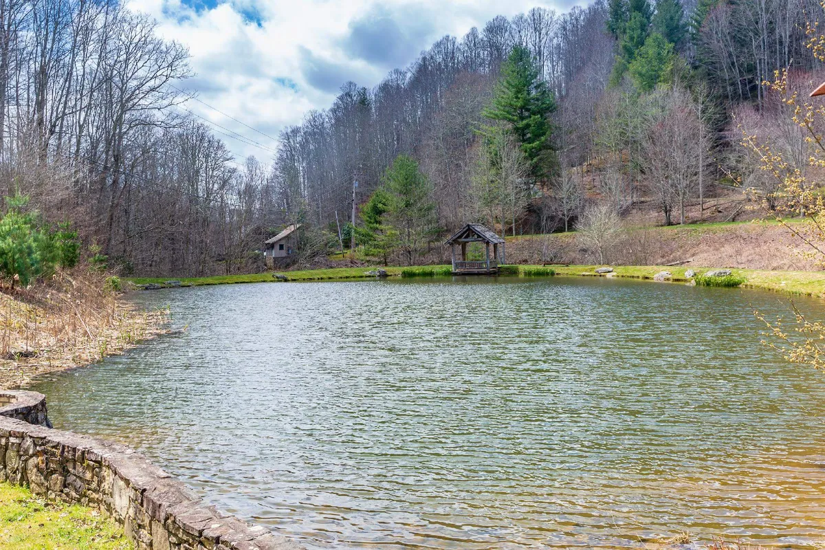 A calm pond framed by lush trees and a wooden gazebo, reflecting the tranquil ambiance of the outdoors and offering opportunities for peaceful moments together.